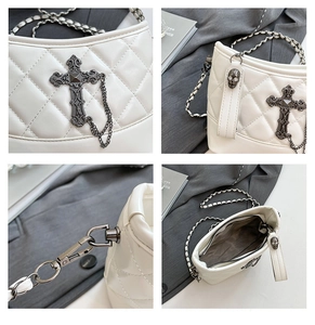 Detail of white quilted bag with gothic cross, skull charm, and internal compartments