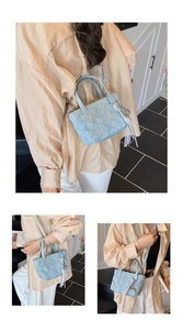 Detail of light blue pleated handbag with detachable strap and lace charm pendant