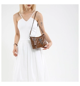 Detail of brown quilted faux leather bag with punk cross and skull charms on shoulder