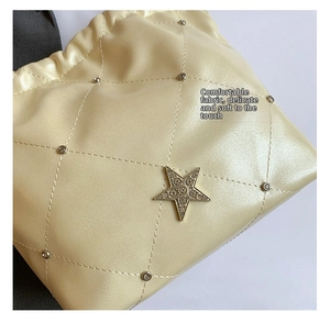 Détail du sac seau matelassé beige avec rivets argentés et étoile scintillante en strass