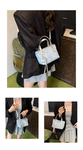 Detail of light blue wrinkled texture handbag with silver handle and metallic tassel charms