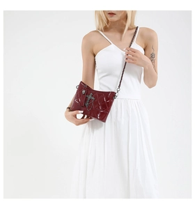 Macro detail of wine red quilted crossbody bag featuring vintage cross and skull charms