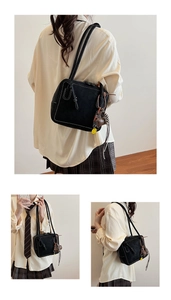 Detail of black tote bag featuring white contrast stitching and yellow smiley charm