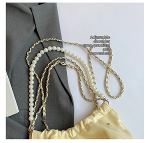 Détail de la bandoulière en perles réglable et chaîne sur sac crème matelassé