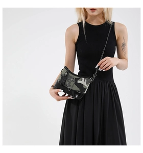 Detail of punk style camo crossbody bag with metal cross charm and black chain strap