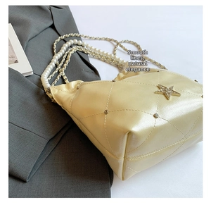 Détail de la chaîne en perles et de l'étoile en strass sur le sac seau matelassé beige
