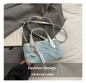 Detail of blue denim textured bucket bag with silver handle and lace tassel accessory