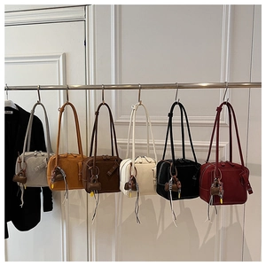 Minimalist square tote bags in six colors with tassels and striped charms on white wall