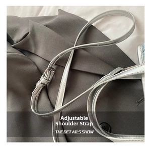 Macro detail showing a thin silver adjustable shoulder strap with metal buckle on grey fabric