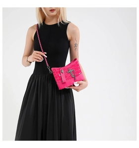 Close-up of fuchsia crocodile texture handbag with metal cross charm on black dress
