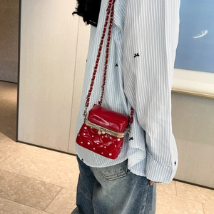 Detail of red quilted crossbody bag with silver studs and metal clasp closure