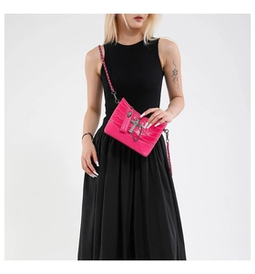 Close-up of pink faux-crocodile bag with cross pendant and metal chain strap detail