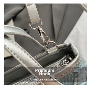 Detail of silver metal zipper and swivel hook on a light blue denim bucket bag