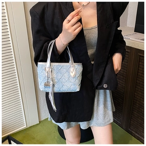 Detail of light blue pleated denim mini tote with silver handles and fringe tassel charm