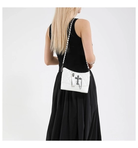 Close-up of white quilted leather bucket bag with gothic cross and chain strap detail