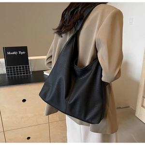 Détail de la texture cuir grainé noir sur un grand sac cabas hobo au style minimaliste