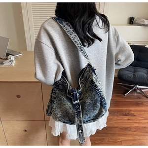 Detail of blue denim hobo bag with metal grommets and wide shoulder strap