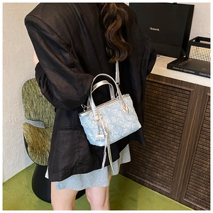 Detail of light blue quilted handbag with silver trim and elegant tassel charm