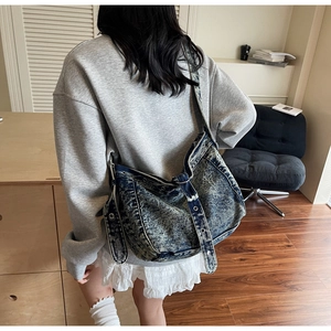 Retro washed denim tote bag with metal eyelet strap detail shown on a model