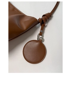 Detailansicht der braunen Ledertasche mit dekorativem Knoten und rundem Anhänger-Detail