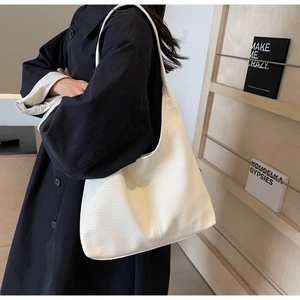 Detailansicht der großen weißen Hobo-Tasche mit Ledertextur auf der Schulter des Models