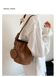 Braune Leder-Eimertasche mit passendem runden Münzfach, präsentiert an der Schulter