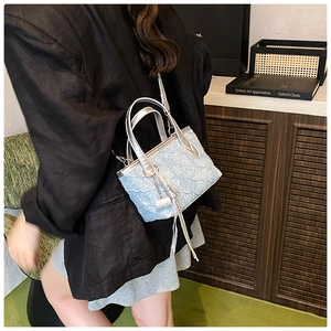 Close-up of light blue textured bucket bag with silver handles and metallic tassels