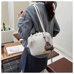 Detail of off-white tote bag with brown mini charm shown in an urban lifestyle setting
