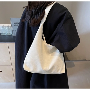 Detailed view of cream leather hobo bag with grainy texture and wide shoulder strap