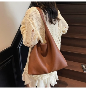 Vista posteriore di una grande borsa a spalla in pelle martellata color caramello su modella