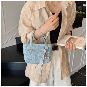 Close-up of light blue mini bucket bag with pleated texture and lace charm details