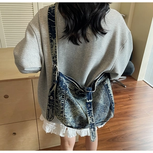 Back view of a model wearing a large vintage washed denim messenger bag with metal eyelets