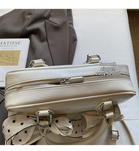 Dettaglio della borsa beige in ecopelle con sciarpa di seta a pois annodata al manico