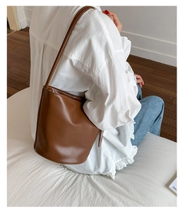 Dunkelbraune PU-Leder-Eimertasche kombiniert mit weißer Bluse und blauer Jeans