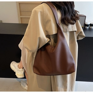 Detailansicht einer großen braunen Leder-Tragetasche mit Struktur auf einem Model