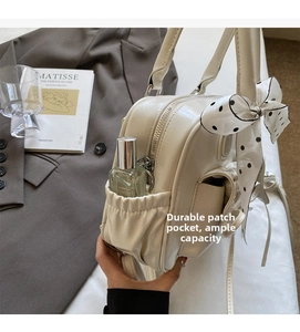 Dettaglio borsa in ecopelle crema con tasca laterale elastica e foulard a pois retrò