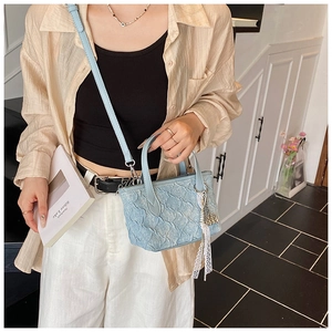 Detail of light blue pleated texture bucket bag with removable strap and lace charm