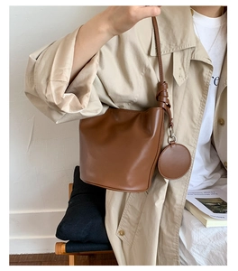 Detail einer braunen matten Leder-Beuteltasche mit rundem Münztäschchen an einem Model