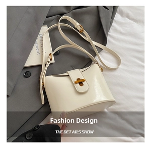 Detail der minimalistischen cremefarbenen Beuteltasche mit Goldverschluss und Glanzoptik
