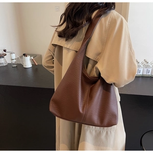 Vue détaillée de la texture du cuir grainé marron foncé et des coutures du grand sac