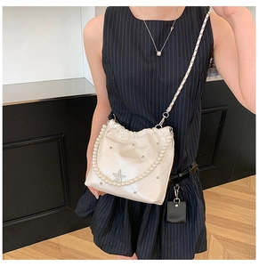 Détail du sac seau blanc avec poignée en perles et emblème étoilé décoratif