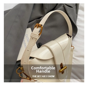 Detail der beigen Ledertasche mit goldenem Drehverschluss und abnehmbarem Schultergurt