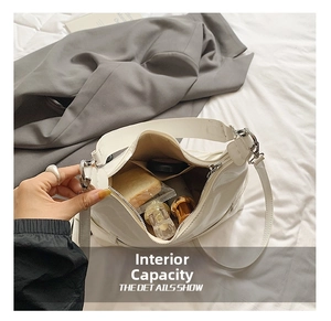 Macro view of white glossy leather underarm bag showing internal capacity and silver zipper