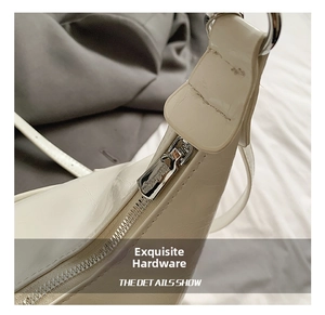 Detailed close-up of shiny cream leather tote featuring premium silver hardware and zipper