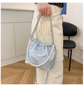 Détail d'un sac bandoulière matelassé bleu clair avec strass étoilés et chaîne de perles