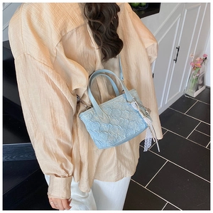 Light blue pleated mini bucket bag with tassel detail worn as a crossbody bag