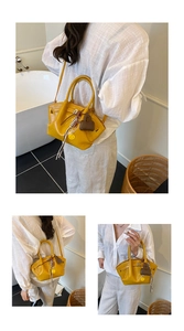 Detail of ginger yellow leather dumpling bag with drawstring lock and cute charms