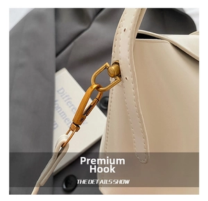 Details des goldfarbenen Metallhakens und der feinen Naht an der cremefarbenen Tasche