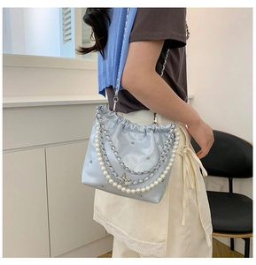 Détail d'un sac seau matelassé bleu clair avec chaîne en perles et pendentif étoile