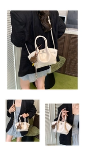 Detail of off-white pleated tote bag with silver buckle and heart charm accessory